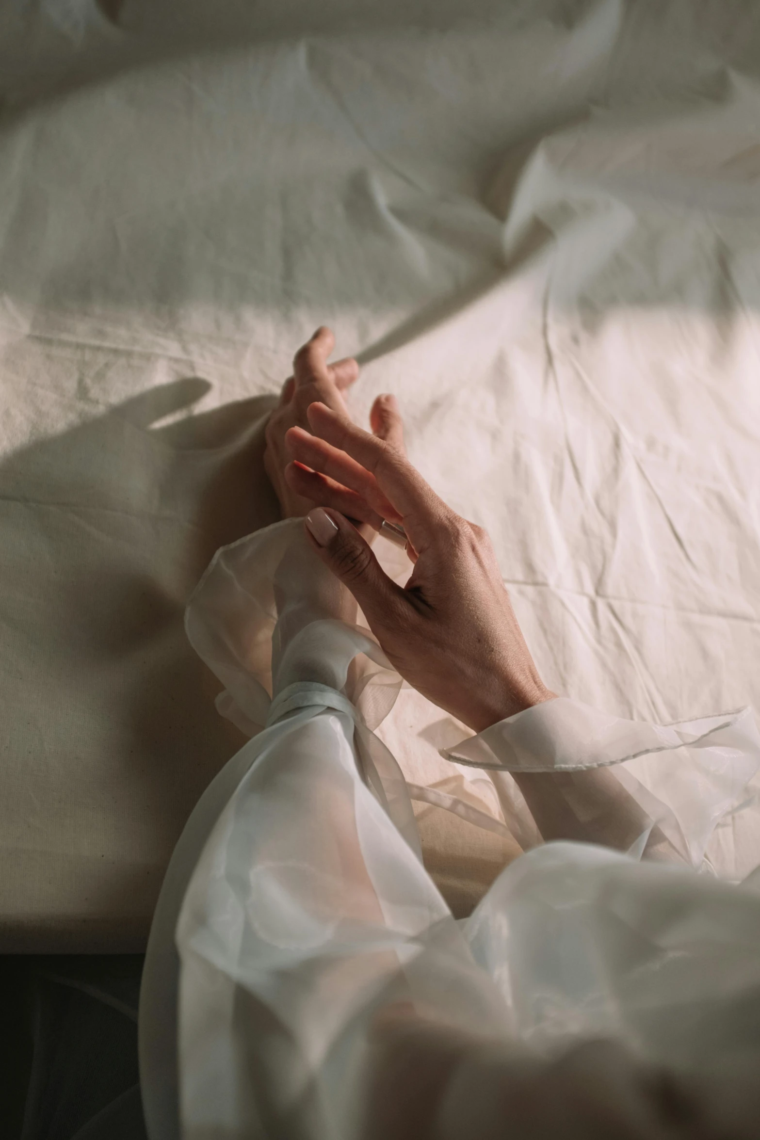 a close up of a person laying on a bed, inspired by Elsa Bleda, trending on pexels, romanticism, white sleeves, soft translucent fabric folds, emanating magic from her palms, ilustration