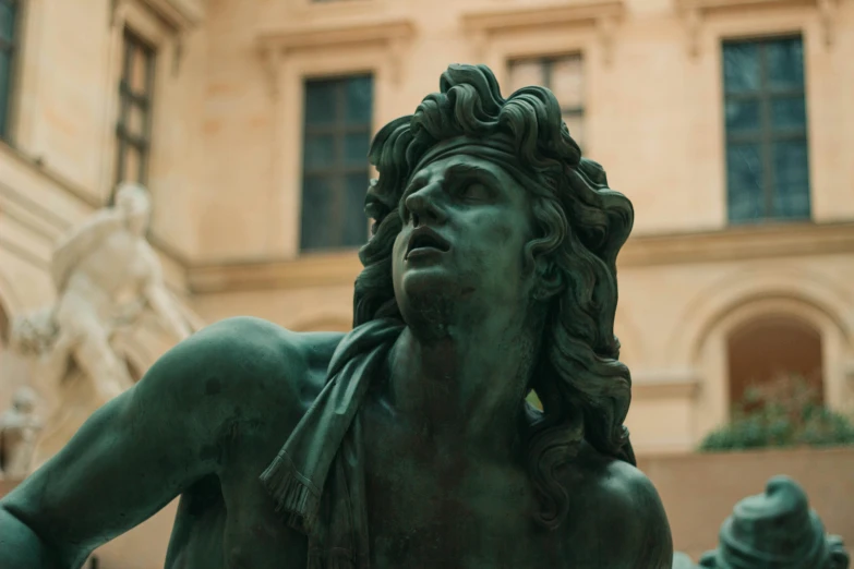 a close up of a statue with a building in the background, by Achille Leonardi, pexels contest winner, neoclassicism, elaborate hair, verdigris, mid-shot of a hunky, looking away from viewer