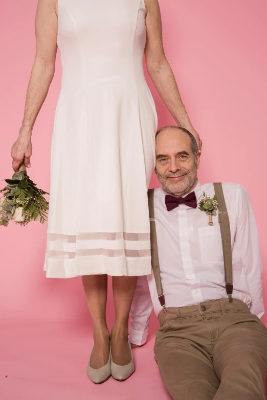 a man sitting next to a woman in a white dress, flowers growing out of its head, photo of a 50-year-old white man, suspenders, promo image