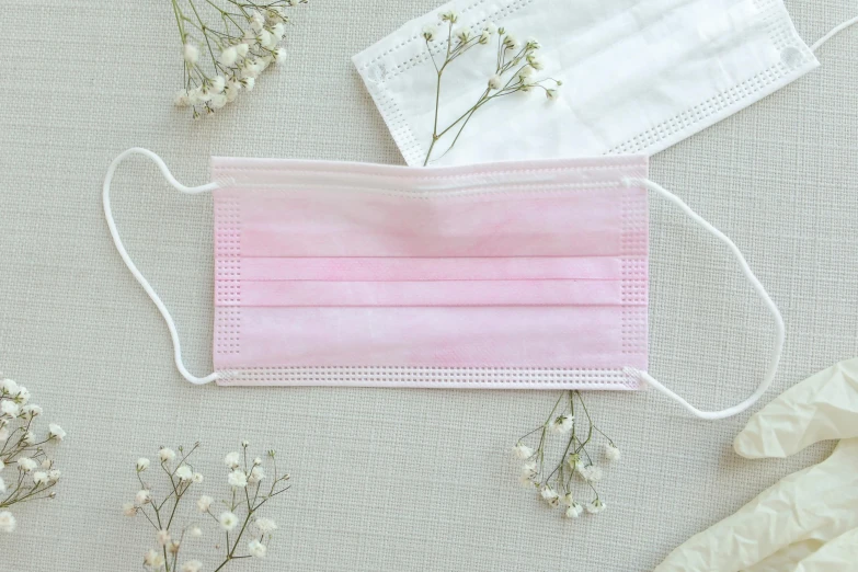 a pink face mask sitting on top of a table, petal pink gradient scheme, made of lab tissue, flat lay, 3 - piece