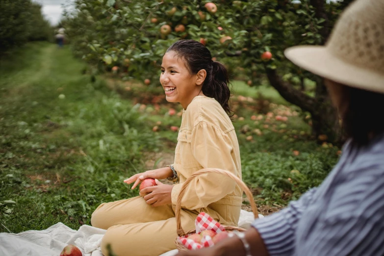 a woman sitting on a blanket in an apple orchard, pexels contest winner, happening, happy friend, person in foreground, avatar image, hispanic