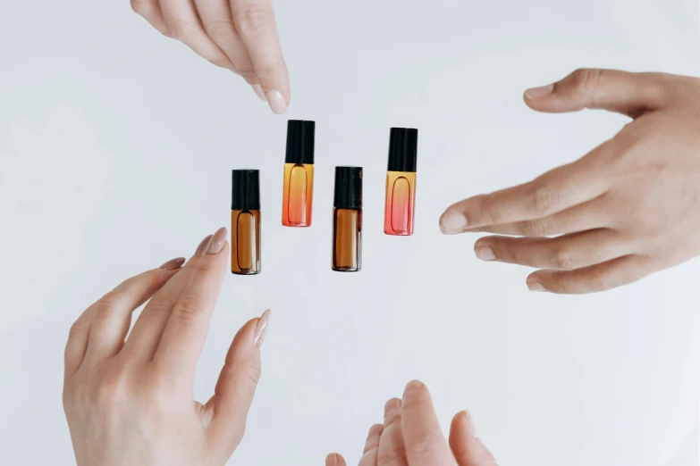 a group of hands reaching for a bottle of nail polish, an album cover, by Emma Andijewska, trending on pexels, gradient orange, apothecary, gradient red to black, miniature product photo