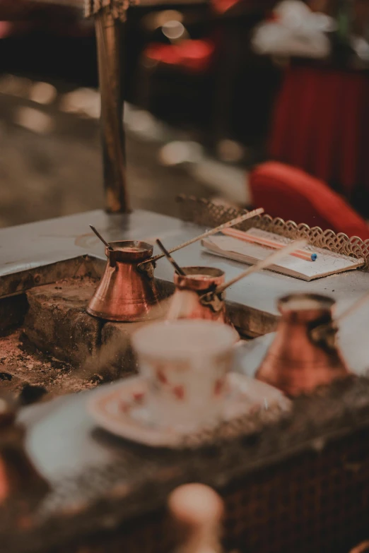 a table that has some cups and saucers on it, by Daniel Lieske, trending on unsplash, renaissance, istanbul, copper, low quality photo, egyptian setting