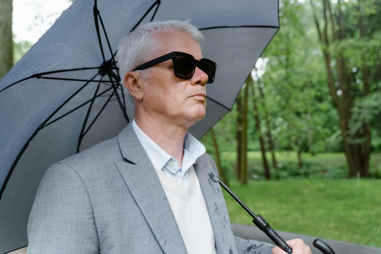 a man in a suit and sunglasses holding an umbrella, unsplash, photorealism, medium length slick white hair, martin parr, andrei tarkovsky, hyperrealism photo