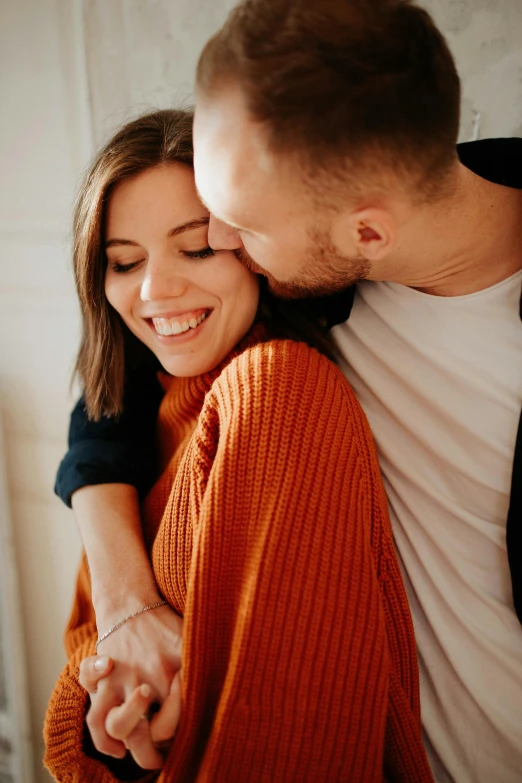 a man and a woman sitting next to each other, a picture, trending on pexels, hugging and cradling, cardigan, licking, orange hue