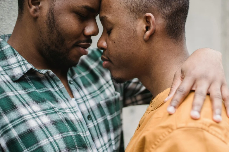 a couple of men standing next to each other, trending on pexels, intimate holding close, african american, multicolored, center of image