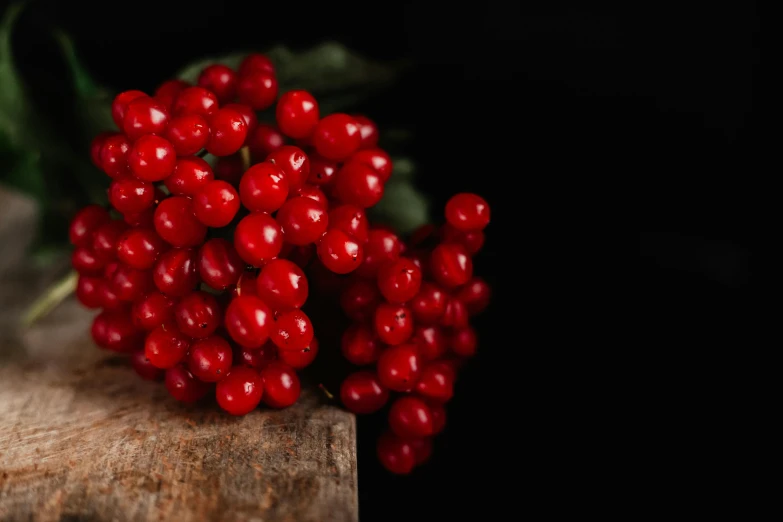 a bunch of red berries sitting on top of a wooden table, profile image, on a dark background, high quality product image”