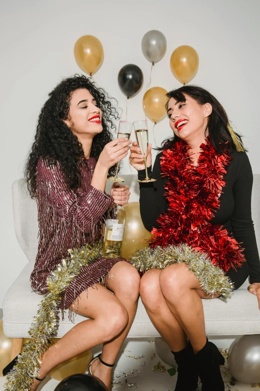 two women sitting next to each other at a party, by Julia Pishtar, pexels, red gold and black outfit, bubbly, with a white background, glitter gif