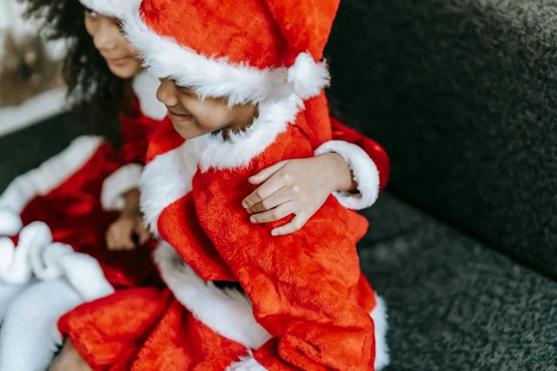 a little girl in a santa suit sitting on a couch, pexels, hurufiyya, close up shot from the side, woman holding another woman, profile image, tiny details