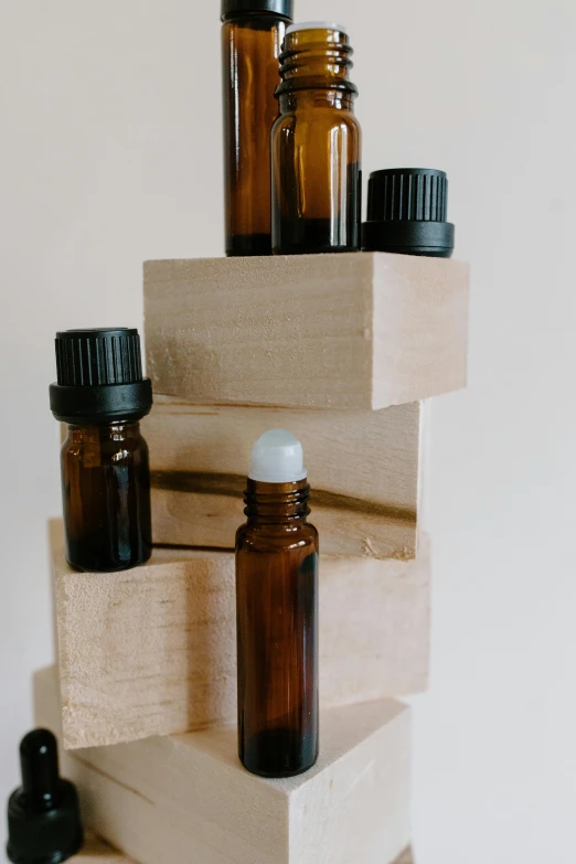 a stack of bottles sitting on top of a wooden block, by Robbie Trevino, apothecary, thumbnail, close-up product photo, small scale