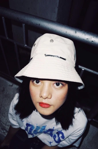 a close up of a person wearing a hat, an album cover, inspired by Gao Cen, she is wearing streetwear, bucket hat, off white, looking the camera