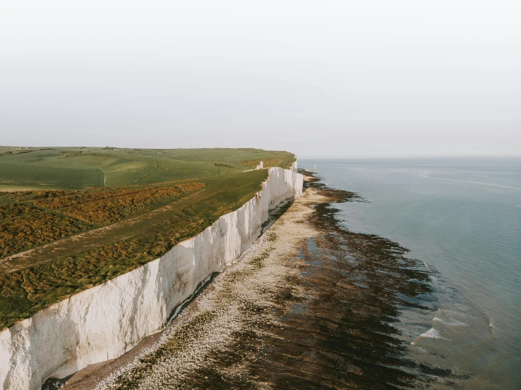 a person standing on top of a cliff next to the ocean, by James Morris, pexels contest winner, renaissance, chalk cliffs above, farming, river flowing through a wall, slightly pixelated