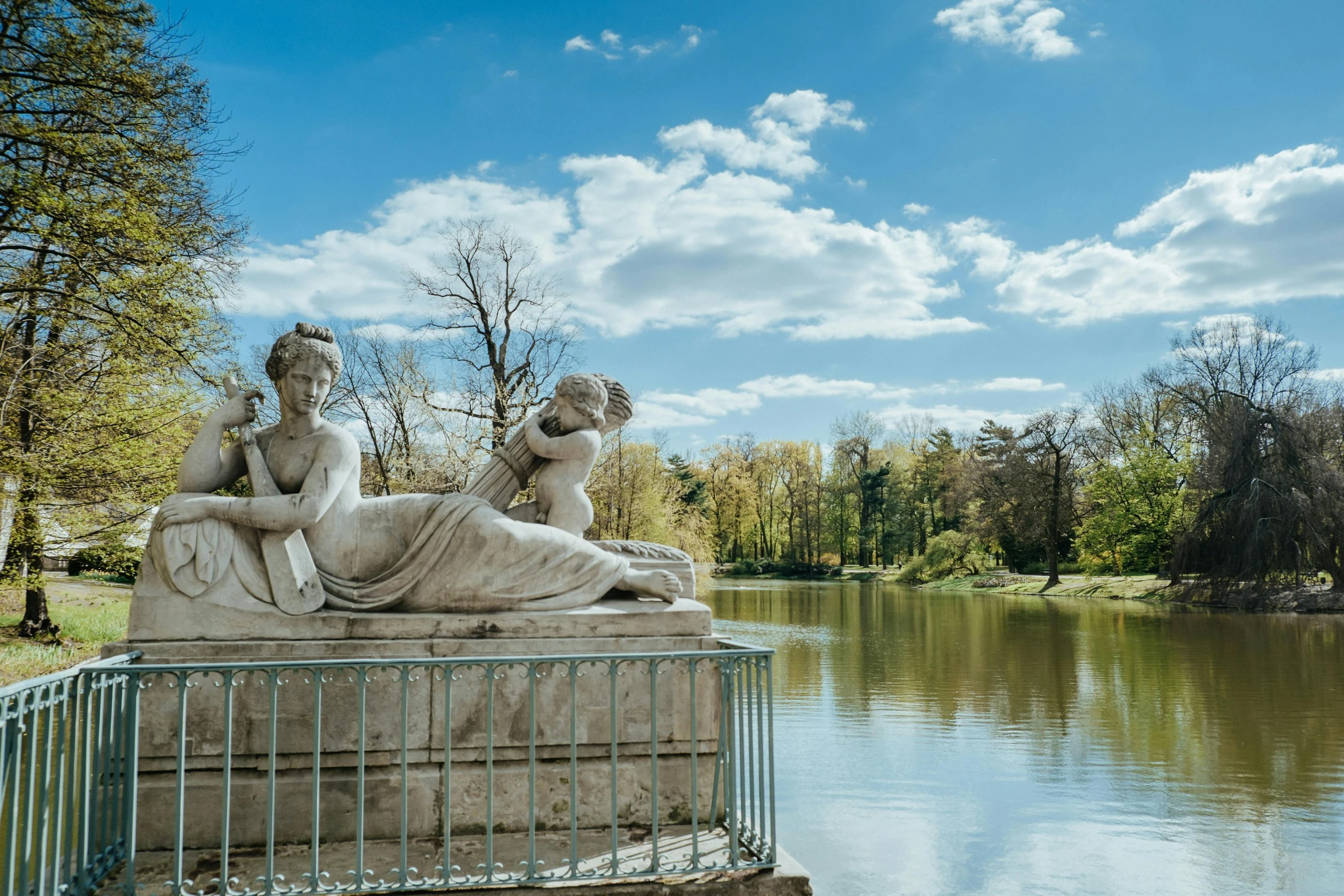 a couple of statues sitting next to a body of water, a statue, by Antoni Brodowski, neoclassicism, sunny day time, wide views