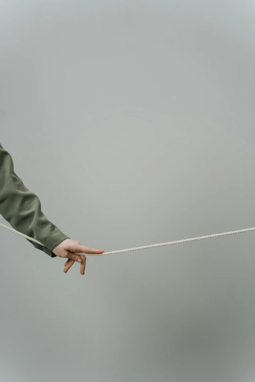 a close up of a person holding a rope, an album cover, unsplash, conceptual art, very long arms, muted green, plain background, low quality photo