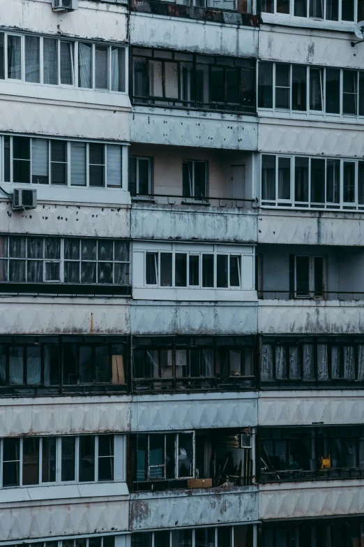 a very tall building with lots of windows, inspired by Elsa Bleda, unsplash, brutalism, photo of poor condition, soviet suburbs, grey, wrecked buildings