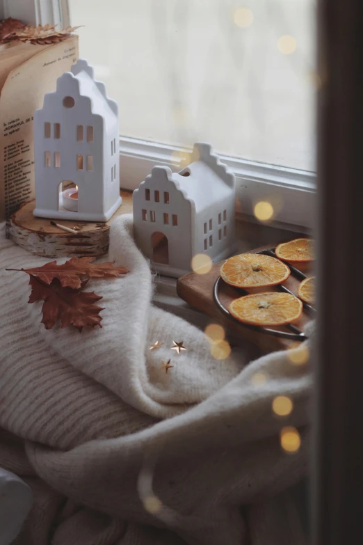 a small white house sitting on top of a window sill, a still life, by Zofia Stryjenska, pexels contest winner, soft diffuse autumn lights, sweets, 🍂 cute, winter scene