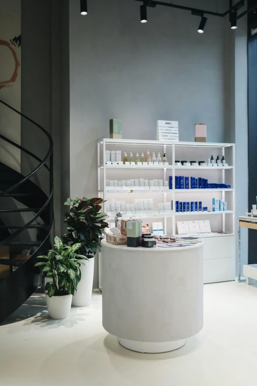 a white counter sitting next to a spiral staircase, unsplash, bauhaus, large jars on shelves, skincare, waiting room, blue