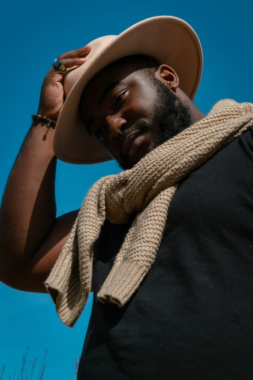 a man wearing a hat and a scarf, by Quinton Hoover, pexels contest winner, symbolism, brown skinned, blue skies, wearing off - white style, photo from a promo shoot