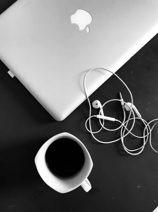 a laptop computer sitting on top of a table next to a cup of coffee, a black and white photo, by Byron Galvez, unsplash, postminimalism, with head phones, square, white on black, professional iphone photo