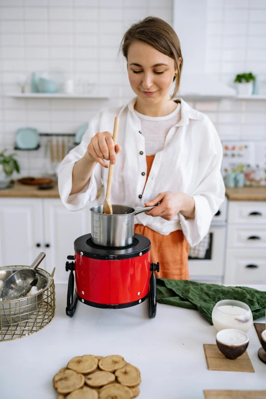 a woman is cooking cookies in the kitchen, by Julia Pishtar, official product photo, churning, easy to use, 4l