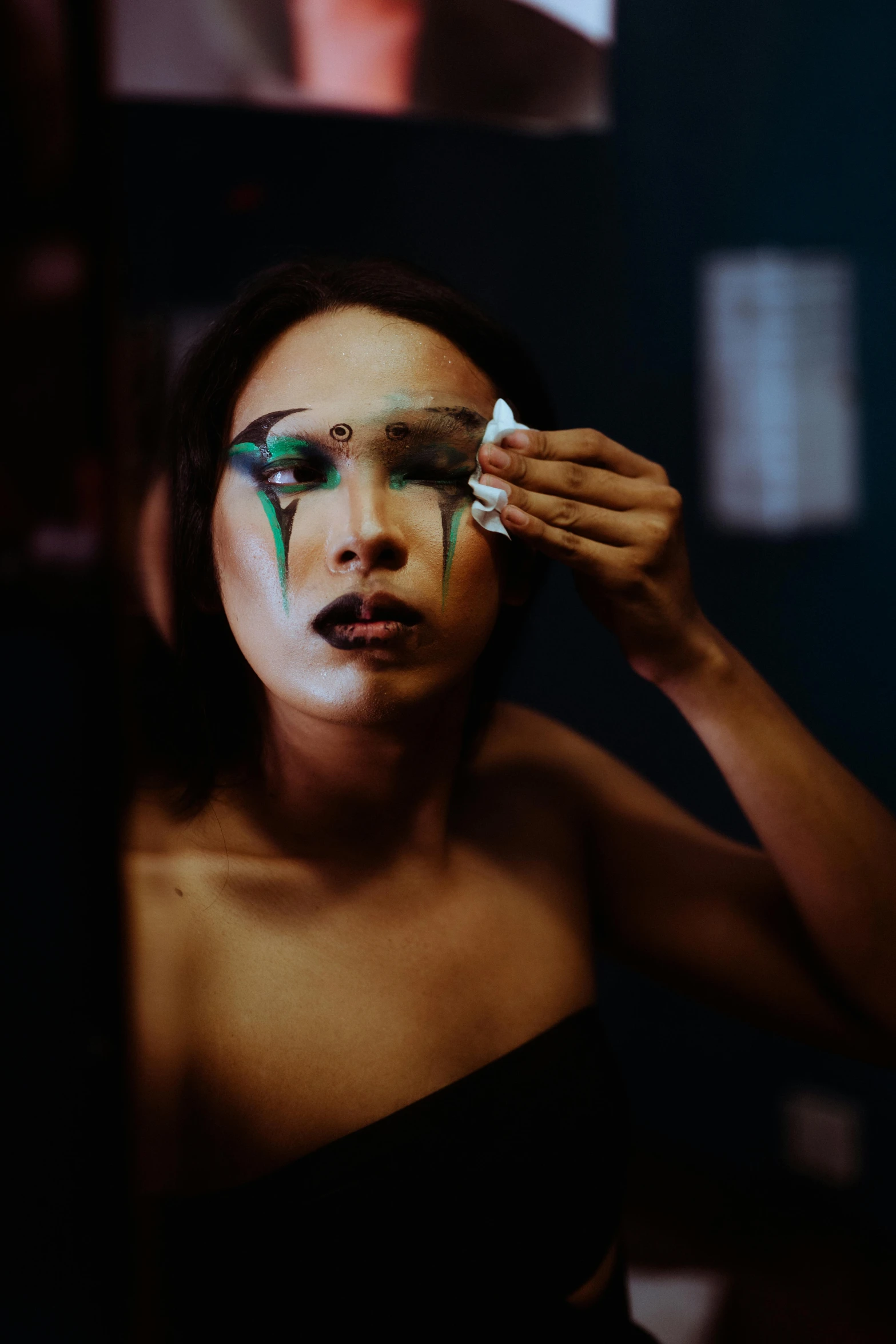 a woman is putting makeup on her face, inspired by Ina Wong, visual art, transgender, tear on face, dramatic lights, posed