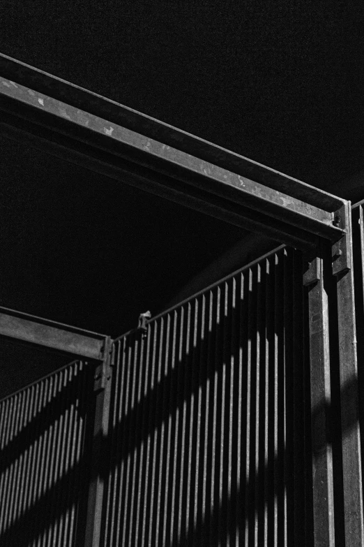 a black and white photo of a building, inspired by Arnold Newman, unsplash, brutalism, shipping containers, fence, 1 9 6 2, detail