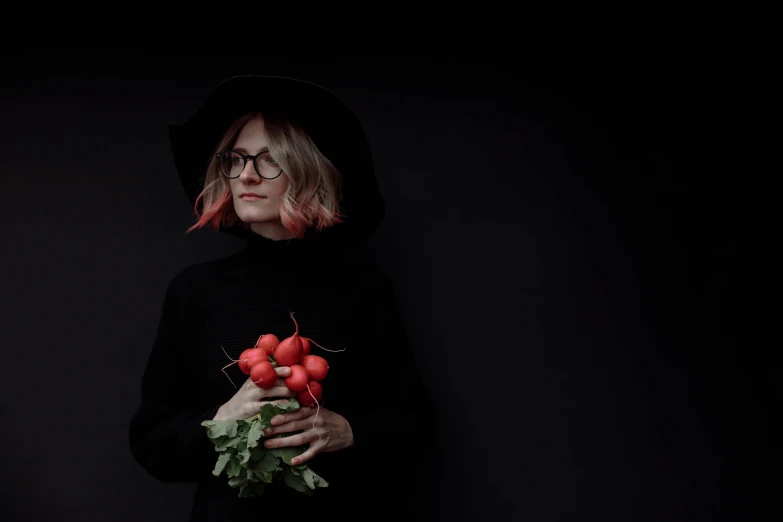 a woman in a black hoodie holding a bunch of radishes, inspired by Anna Füssli, pexels contest winner, portrait of a witch, wearing thin large round glasses, 15081959 21121991 01012000 4k, dark minimal outfit