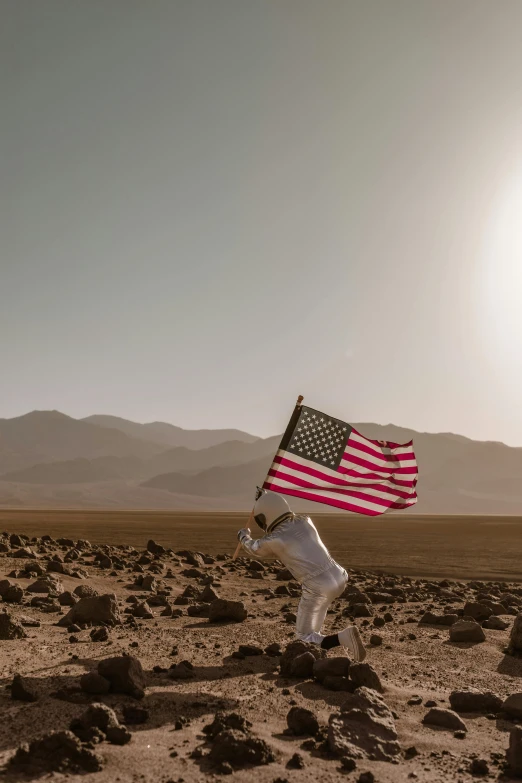 a person holding an american flag in the desert, pexels contest winner, astronauts, low quality photo, brown, celebration