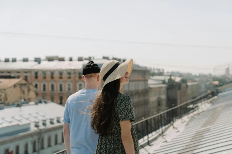 a man and a woman standing on top of a building, by Emma Andijewska, pexels contest winner, wearing a cute hat, looking from behind, russian girlfriend, 15081959 21121991 01012000 4k