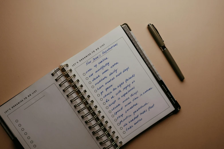 a notepad sitting on top of a table next to a pen, listing image, a list cast, middle of the page, thumbnail