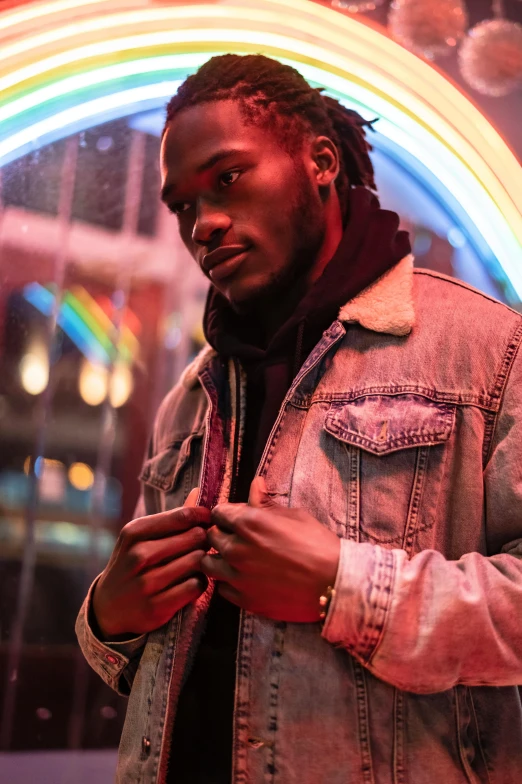 a man in a denim jacket looking at his cell phone, an album cover, trending on pexels, dark skin tone, neon lights in the background, model wears a puffer jacket, gentelman