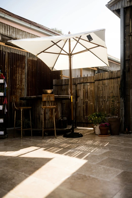 a white umbrella sitting on top of a patio, by Jan Tengnagel, afternoon sun, rustic setting, in chippendale sydney, studio lit