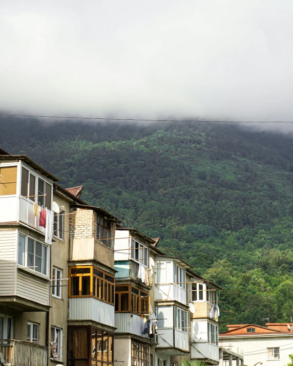 a group of buildings sitting on the side of a road, by Muggur, trending on unsplash, hurufiyya, city of armenia quindio, misty mountains, neighborhood outside window, scandinavian