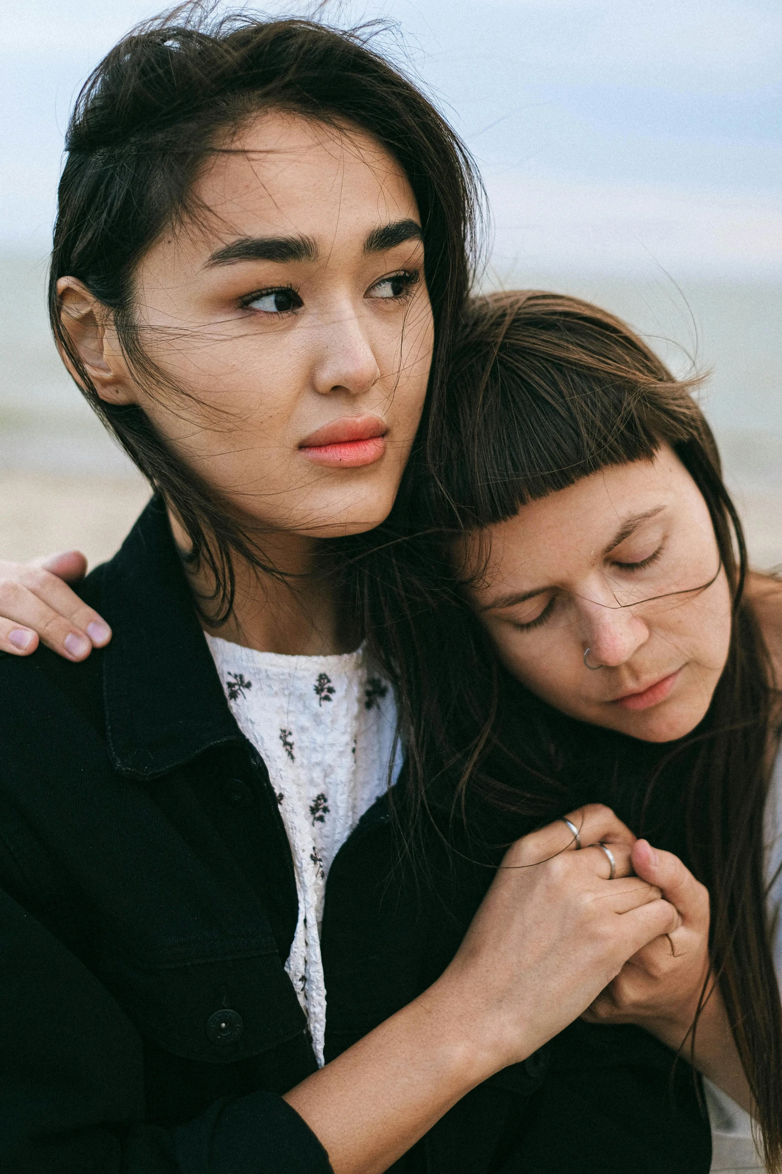 two women standing next to each other on a beach, trending on pexels, renaissance, portrait of mournful, ruan jia and greg rutkowski, lesbian, brunette