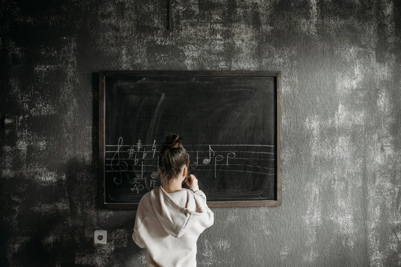 a woman standing in front of a blackboard, an album cover, pexels contest winner, darkslategray wall, music notes, little kid, wall painting