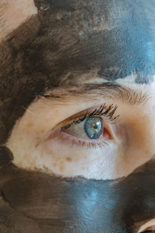 a close up of a person with a mask on, brown watery eyes, charcoal skin, skincare, black and blue eyes