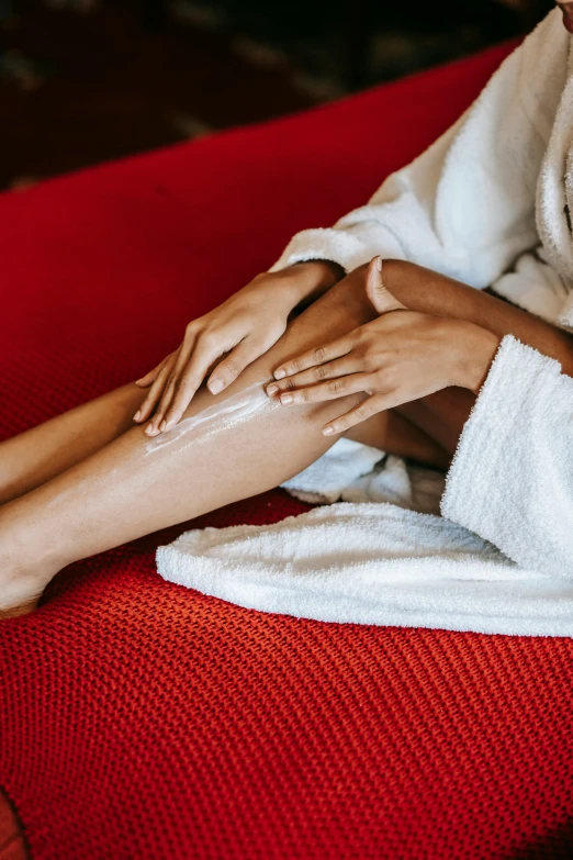 a woman in a bathrobe sitting on a red couch, by Julia Pishtar, trending on pexels, renaissance, thigh skin, cream, scratches, very long