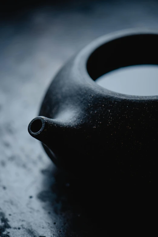 a black tea pot sitting on top of a table, inspired by Tani Bunchō, unsplash, process art, detail texture, made of rubber, round format, dew