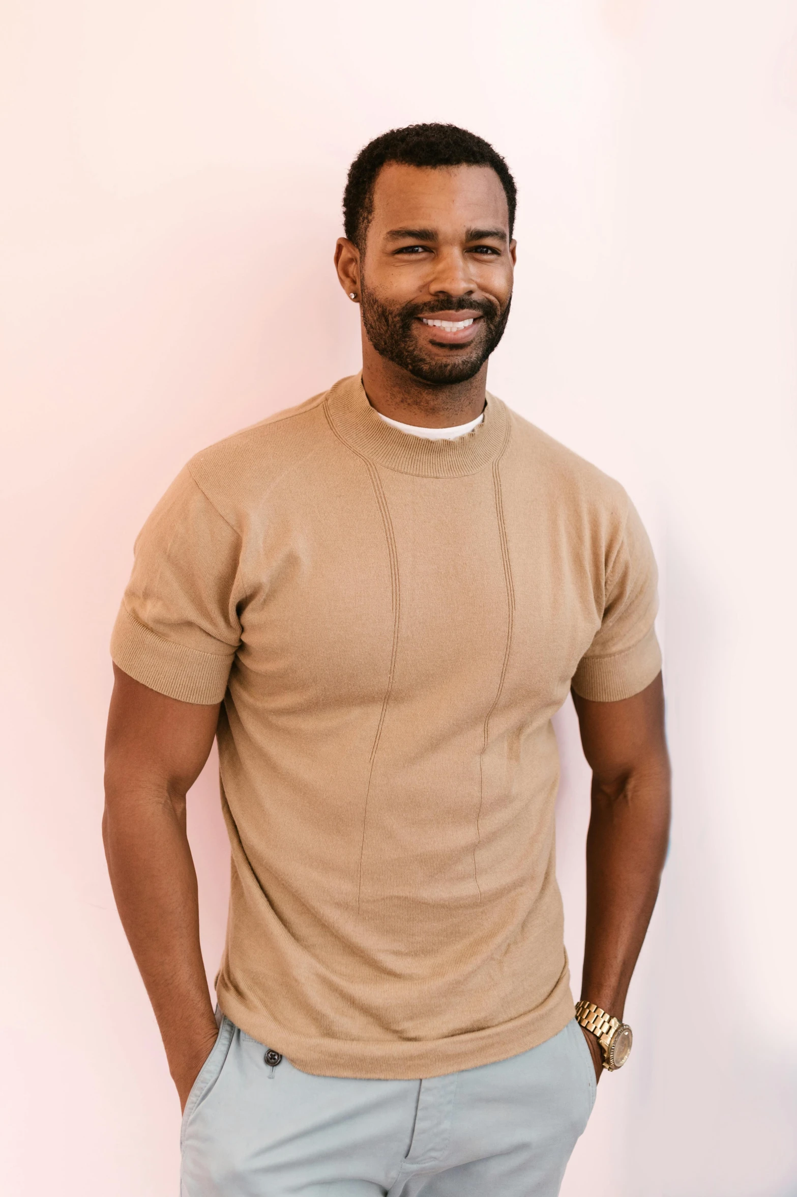 a man standing in front of a white wall, wearing a cute top, aaron brooks, wear's beige shirt, raphael lecoste