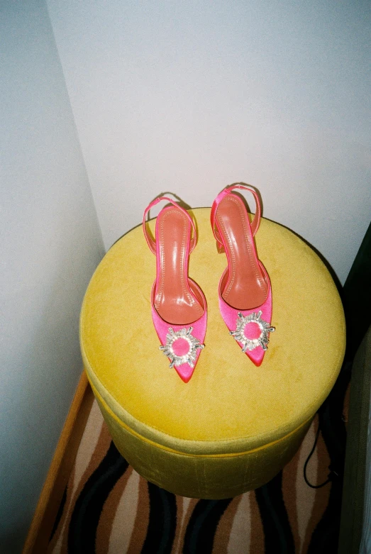 a pair of pink shoes sitting on top of a yellow stool, inspired by Manolo Millares, instagram, renaissance, body covers with neon crystals, vintage aesthetic, terry richardson, high angle shot