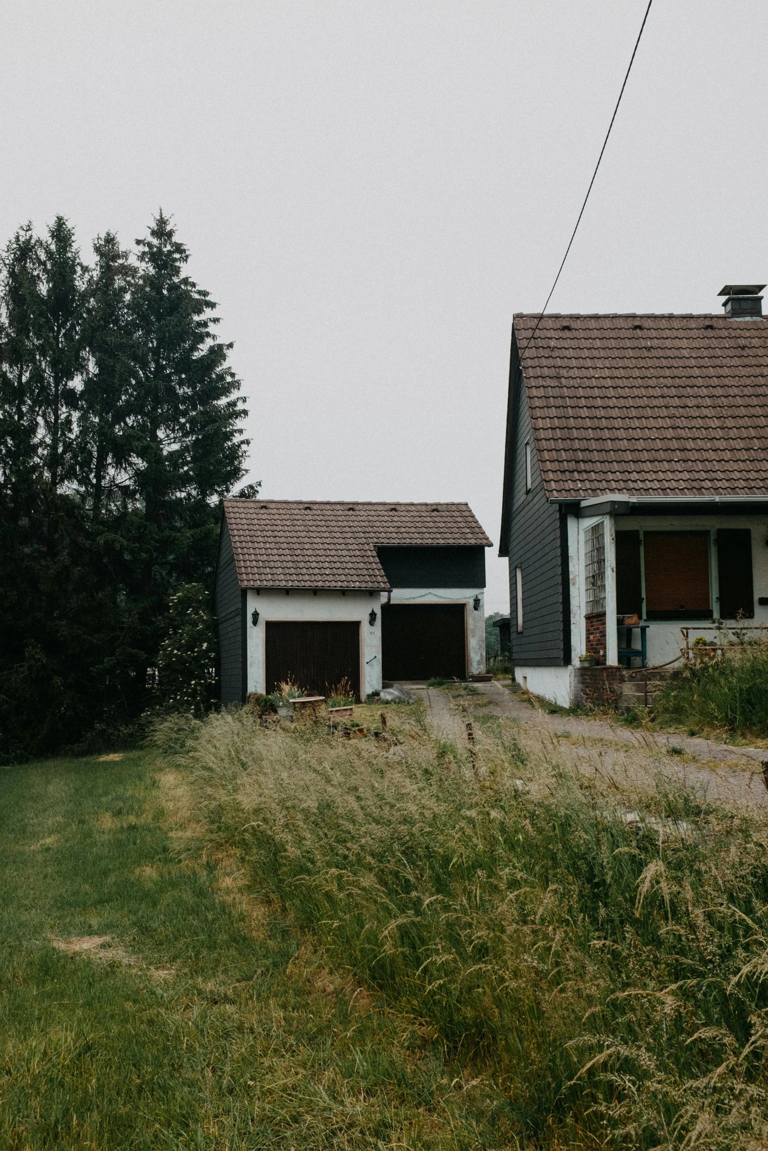 a couple of houses sitting on top of a lush green field, a picture, unsplash, postminimalism, a ghetto in germany, low quality photo, abandoned cottage, driveway