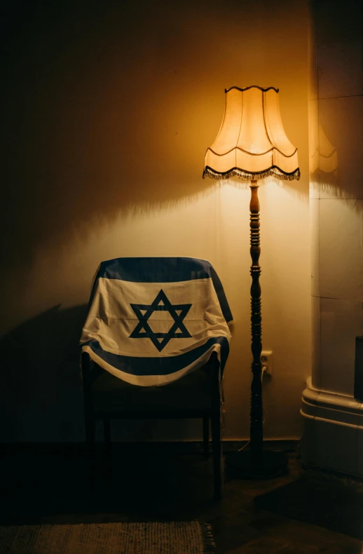 a chair sitting next to a lamp in a room, inspired by Israel Tsvaygenbaum, pexels, flag, candlelit, front facing, religious