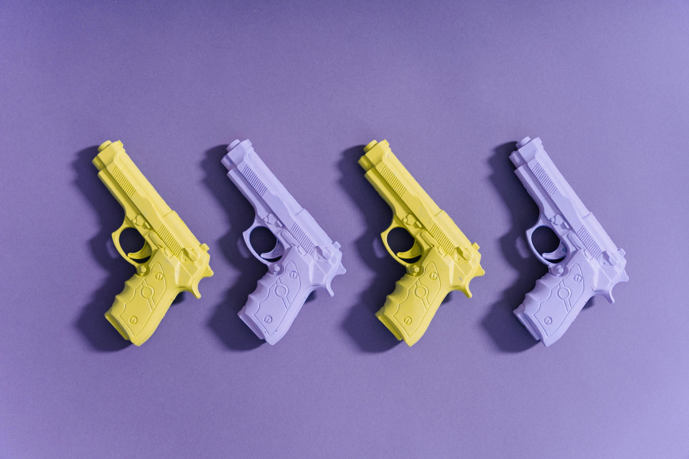 a row of toy guns sitting on top of a purple surface, lavander and yellow color scheme, 3 d print, holding a pistol, high quality product image”