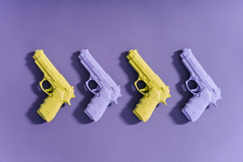 a row of toy guns sitting on top of a purple surface, lavander and yellow color scheme, 3 d print, holding a pistol, high quality product image”