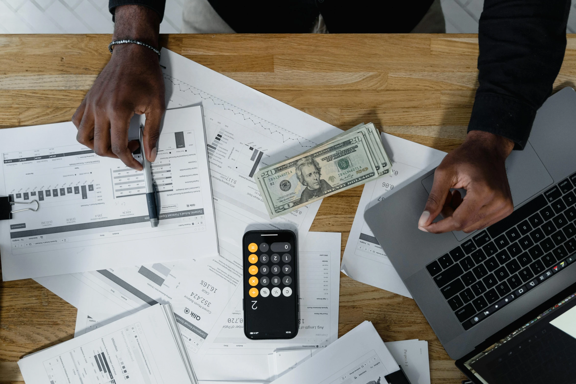 a person sitting at a table with a laptop and a calculator, a photo, by Matt Cavotta, pexels contest winner, hurufiyya, piles of money, 🎨🖌️, jemal shabazz, bottom angle