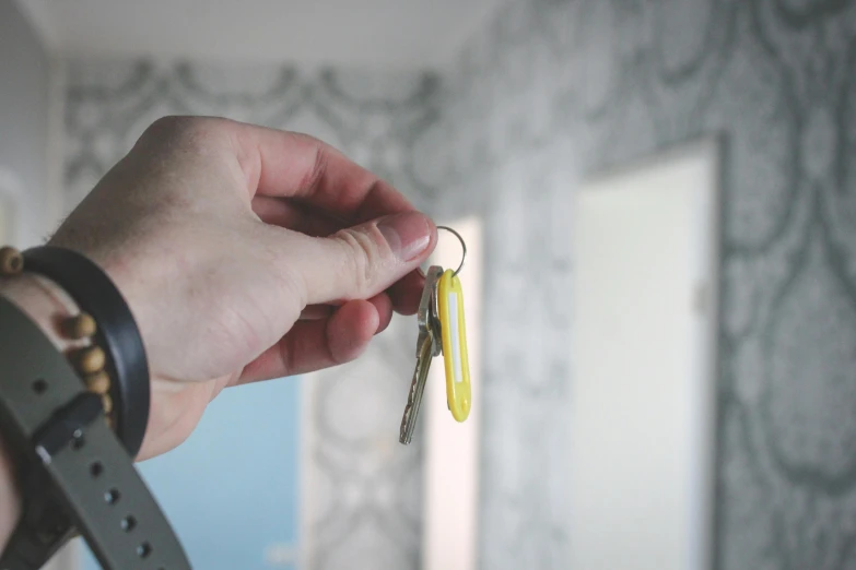 a person holding a bunch of keys in their hand, inspired by Cerith Wyn Evans, pexels, yellow wallpaper, hotel room, open plan, wide shot photograph