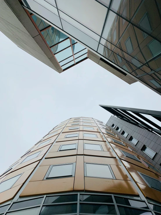 a couple of tall buildings next to each other, inspired by Zaha Hadid, unsplash, helsinki, worm\'s eye view, golden windows, exterior photo