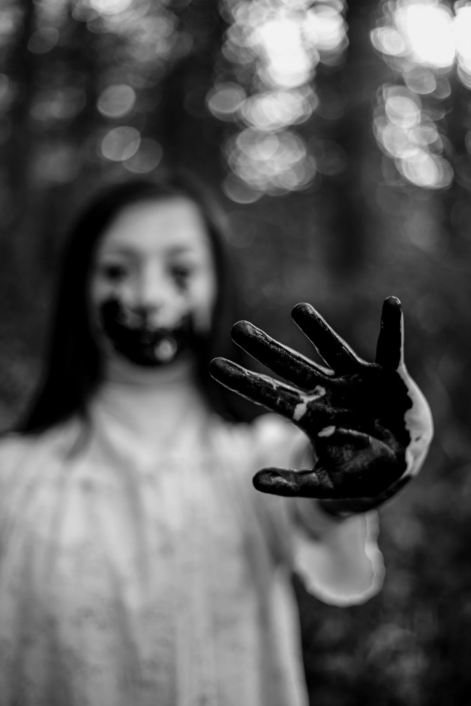 a woman with black paint on her face and hands, a black and white photo, inspired by Brooke Shaden, pexels contest winner, waving at the camera, childhood, stained and bleeding, ✨🕌🌙