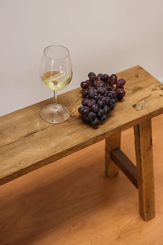 a wooden table topped with a glass of wine next to a bunch of grapes, inspired by Jan Kupecký, bench, product display photograph, square, white