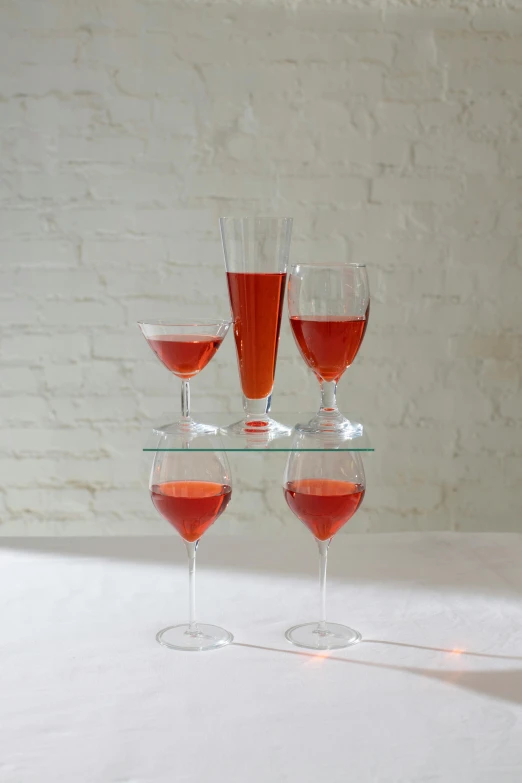 a stack of wine glasses sitting on top of a table, inspired by Jacopo Bellini, renaissance, coral red, tall iced tea glass, large tall, multiple levels